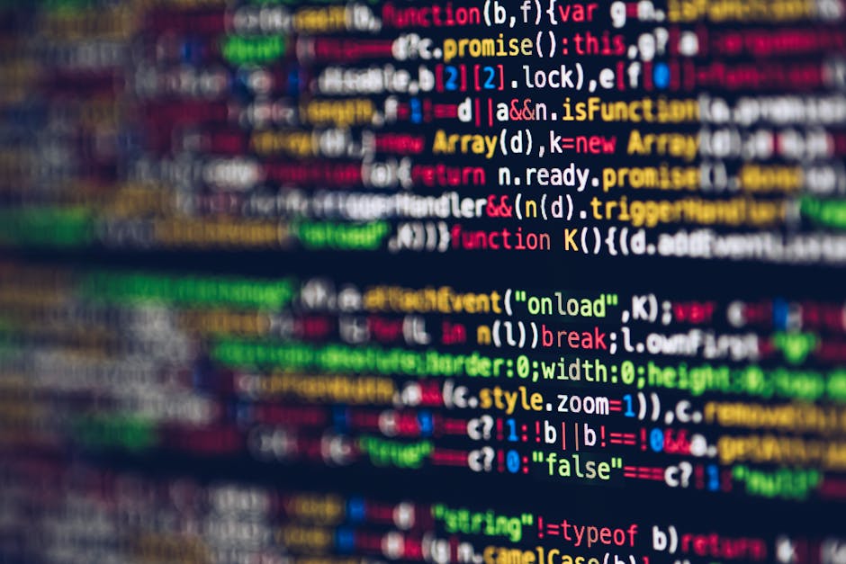 Photograph of a computer screen displaying lines of programming code with syntax highlighting in multiple colors, including red, green, blue, yellow, and white. The code appears slightly out of focus,